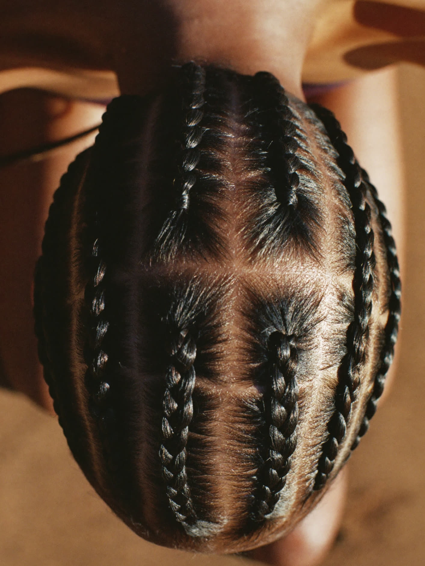 Tresses collées formant un motif géométrique sur le crâne.