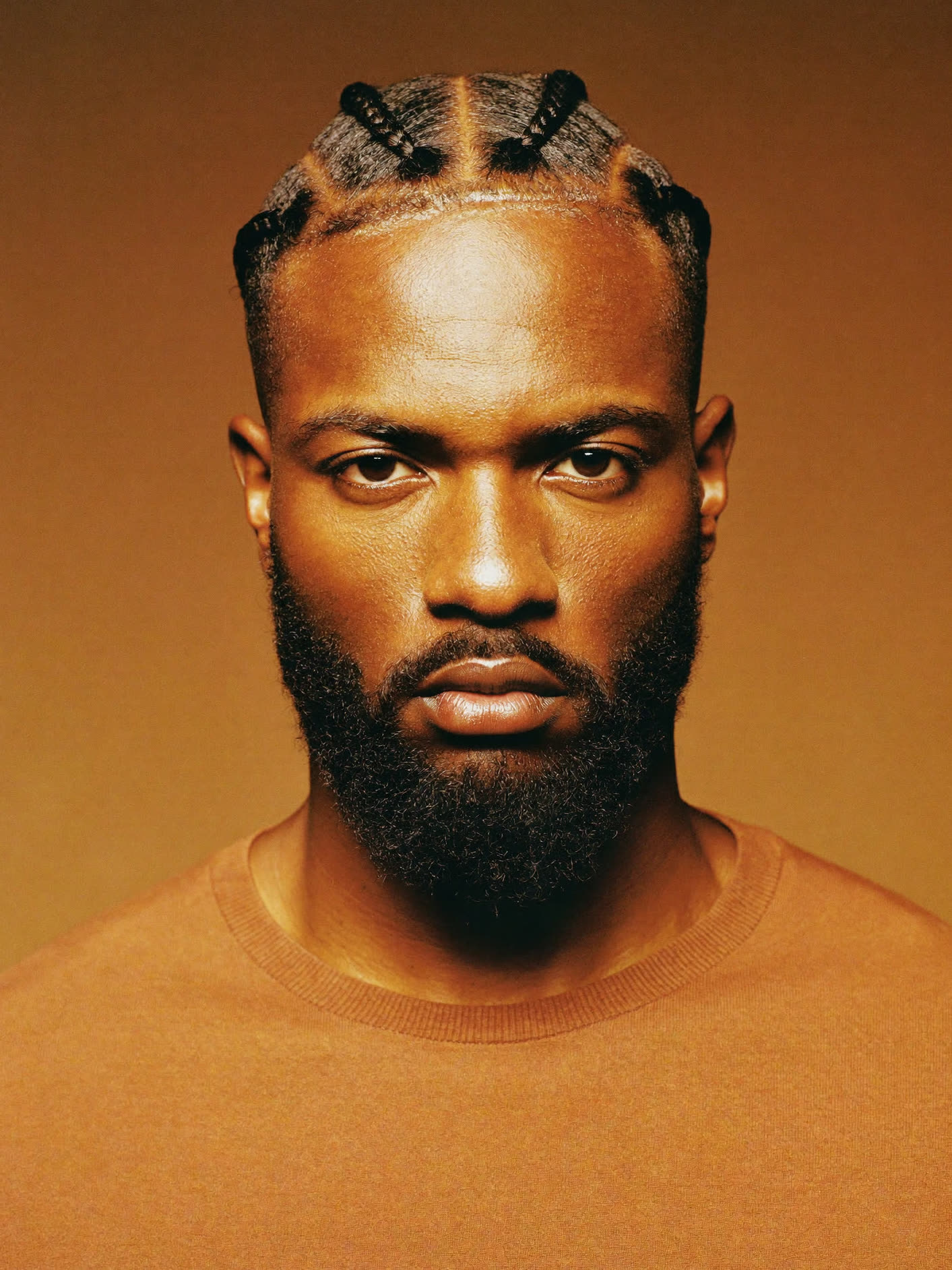Portrait de face d'un homme noir portant des twists courtes régulières, dégradé net et barbe structurée.